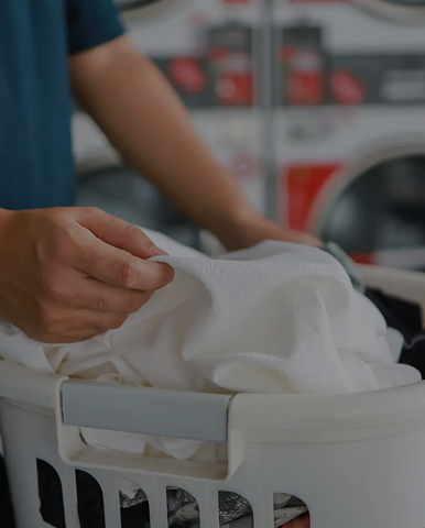 Hands placing white clothes into laundry basket