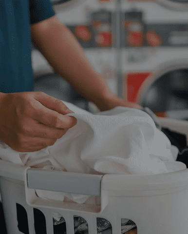 Hands placing white clothes into laundry basket